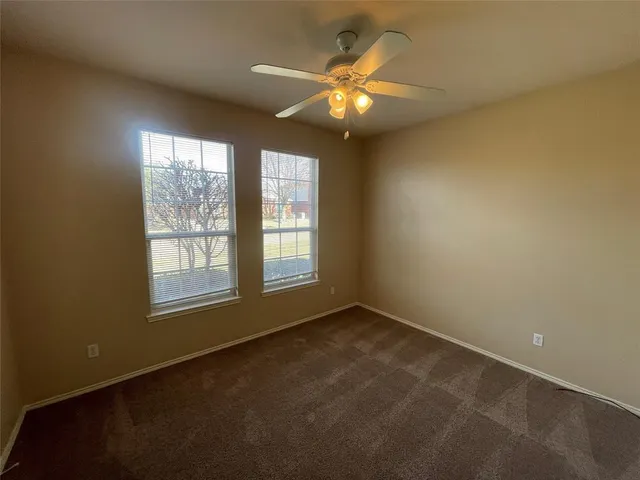 an empty room with a chandelier fan and window