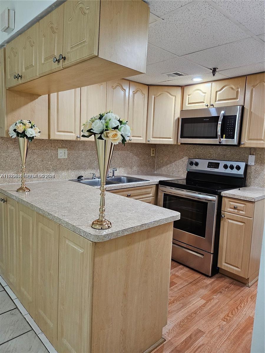 10641 Southwest 108th Avenue, Unit 1H Miami, FL 33176 - Photo 11 of 22 a kitchen with stainless steel appliances a sink a stove a microwave a sink a refrigerator and cabinets