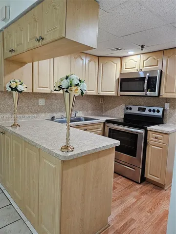 a kitchen with stainless steel appliances a sink a stove a microwave a sink a refrigerator and cabinets