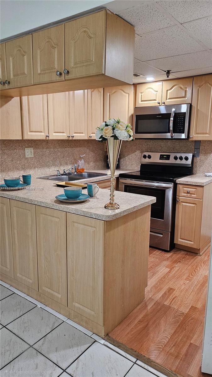 10641 Southwest 108th Avenue, Unit 1H Miami, FL 33176 - Photo 7 of 22 a kitchen with kitchen island granite countertop a sink cabinets and stainless steel appliances