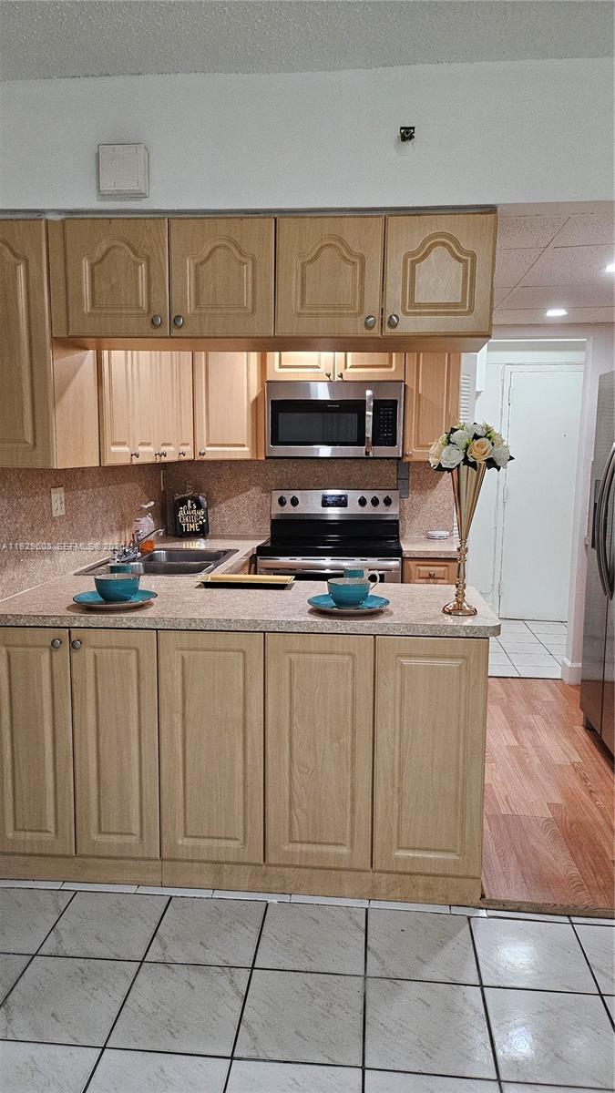 10641 Southwest 108th Avenue, Unit 1H Miami, FL 33176 - Photo 9 of 22 a kitchen with stainless steel appliances a stove a sink and a microwave