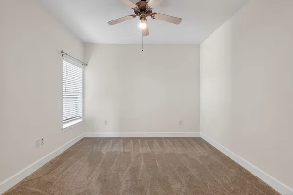 an empty room with a window and a fan