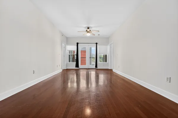 an empty room with wooden floor and windows