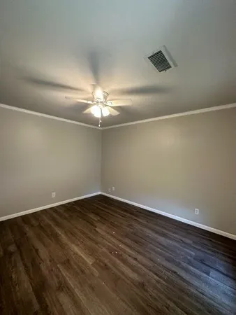 a view of an empty room with wooden floor and chandelier