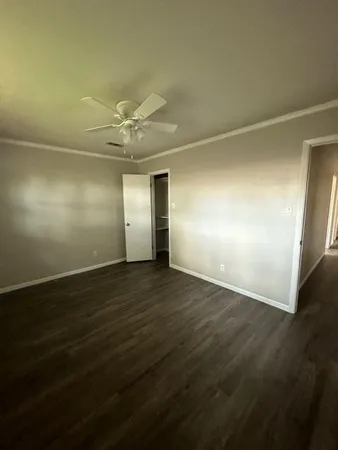 an empty room with wooden floor and fan