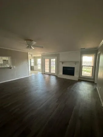 an empty room with wooden floor fireplace and windows