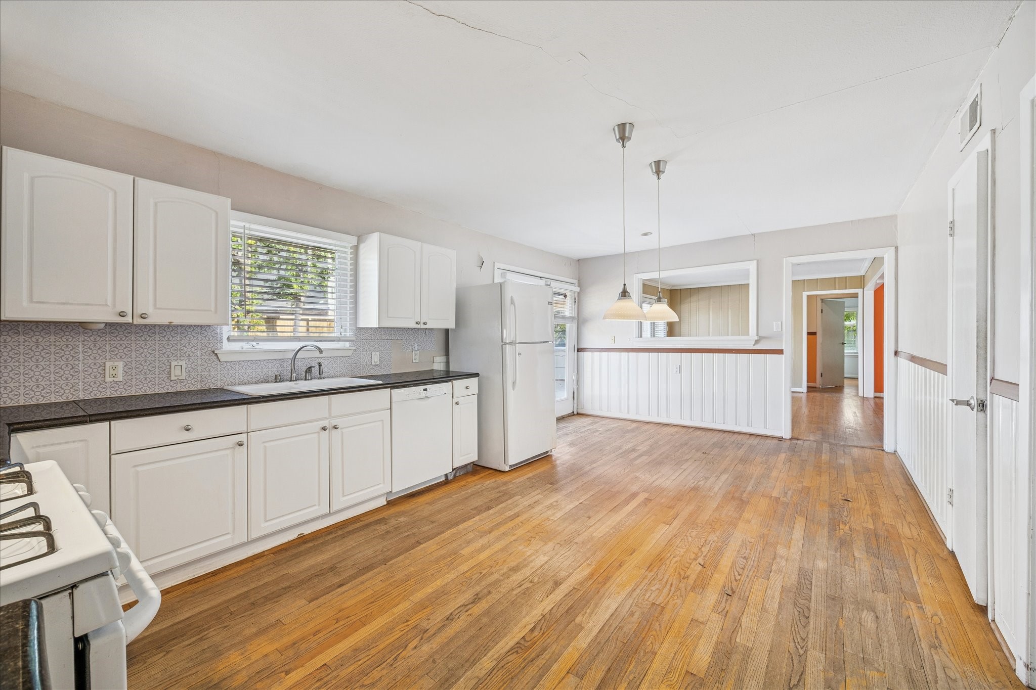 8419 Bluegate Court Houston, TX 77025 - Photo 5 of 12 a large kitchen with wooden floors and white cabinets