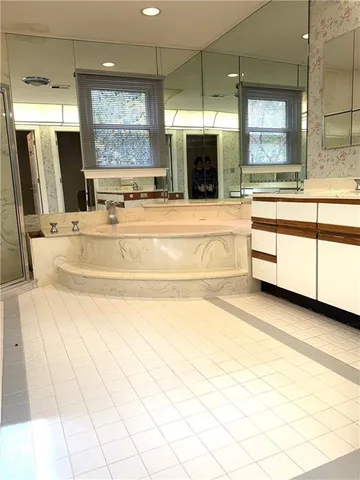 a spacious bathroom with a large tub sink shower and mirror