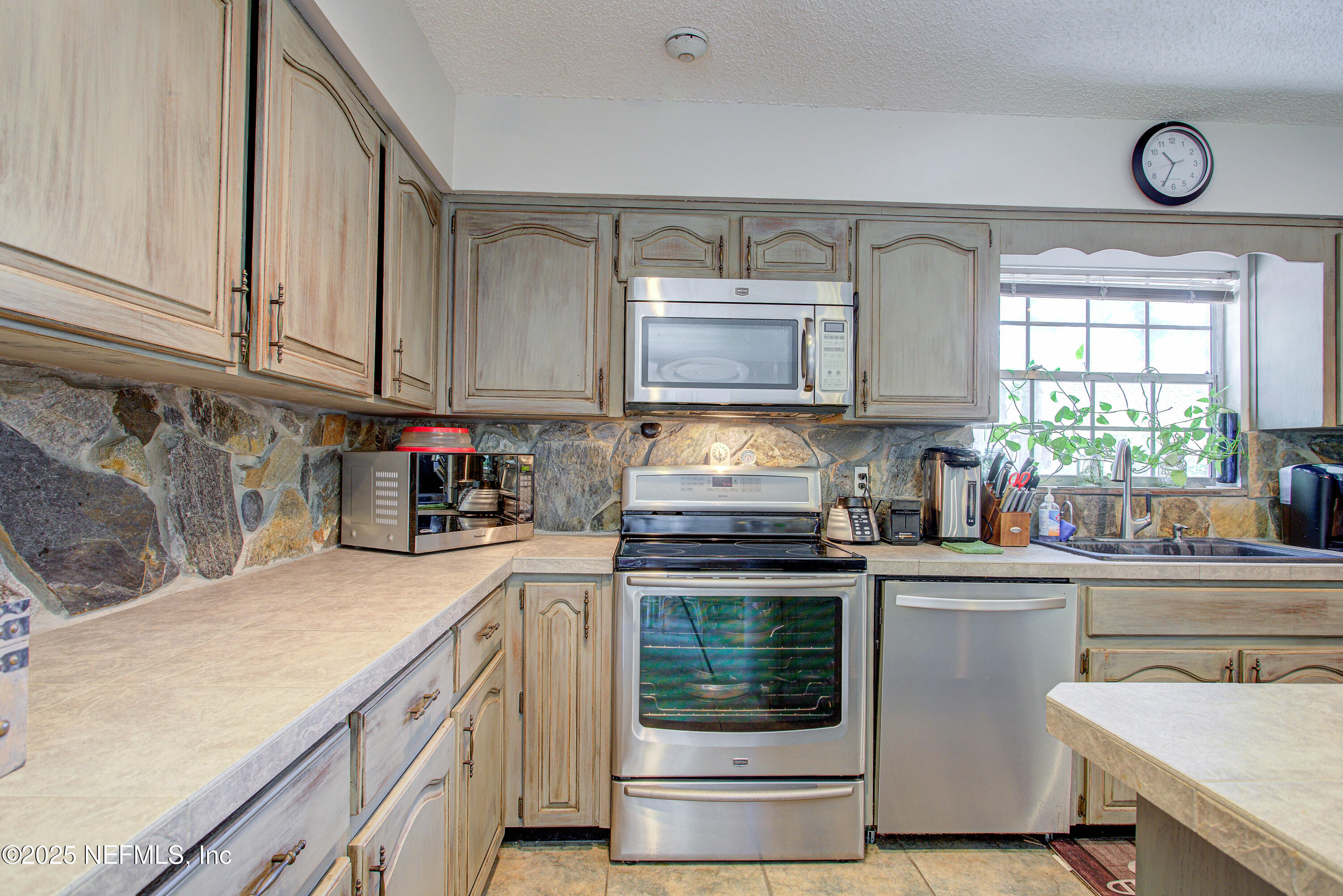 4302 Buck Point Road Jacksonville, FL 32210 - Photo 31 of 74 a kitchen with granite countertop a sink cabinets stainless steel appliances and a window