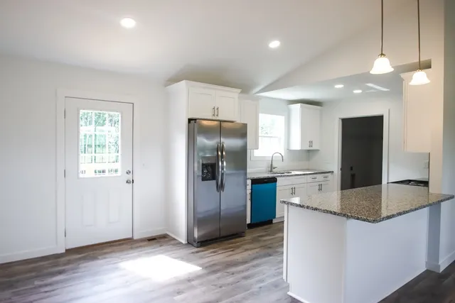 a kitchen with stainless steel appliances granite countertop a refrigerator a sink a stove a microwave and island with wooden floor