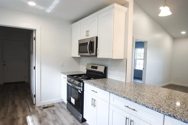 a kitchen with granite countertop a sink cabinets and stainless steel appliances
