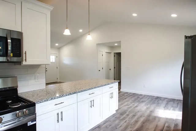 a kitchen with granite countertop a stove a sink and a refrigerator