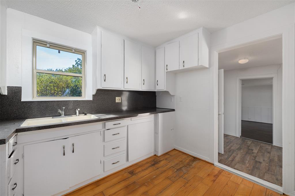 102 San Saba Avenue Benbrook, TX 76126 - Photo 9 of 25 a kitchen with white cabinets a sink and dishwasher with wooden floor