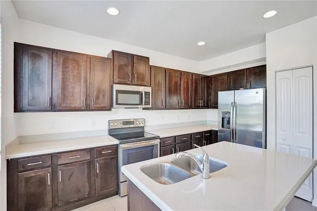 a kitchen with stainless steel appliances a sink a microwave a refrigerator and cabinets