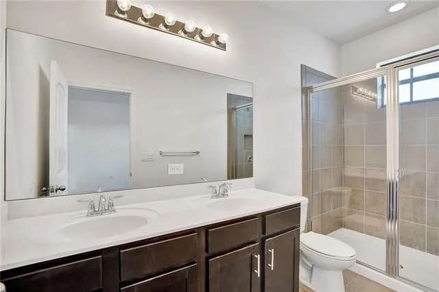 a bathroom with a sink a toilet a mirror and shower