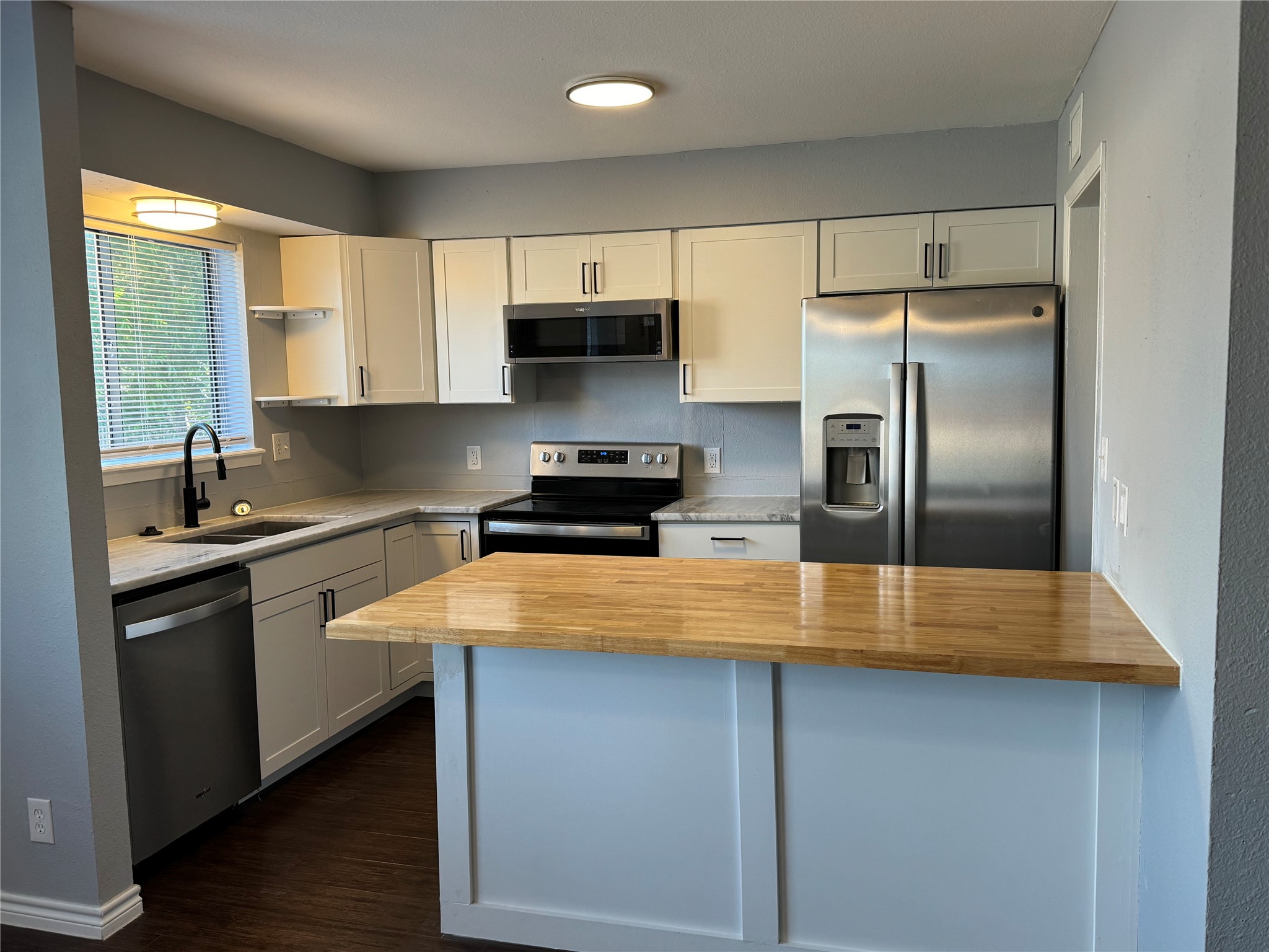 1221 Houston Street, Unit 1 Rosenberg, TX 77471 - Photo 2 of 11 a kitchen with stainless steel appliances a sink a stove a refrigerator a microwave a sink and cabinets