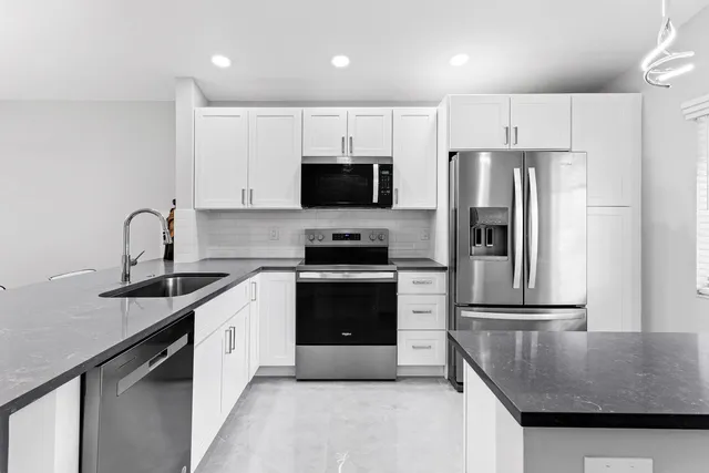 a kitchen with granite countertop a refrigerator stove and sink
