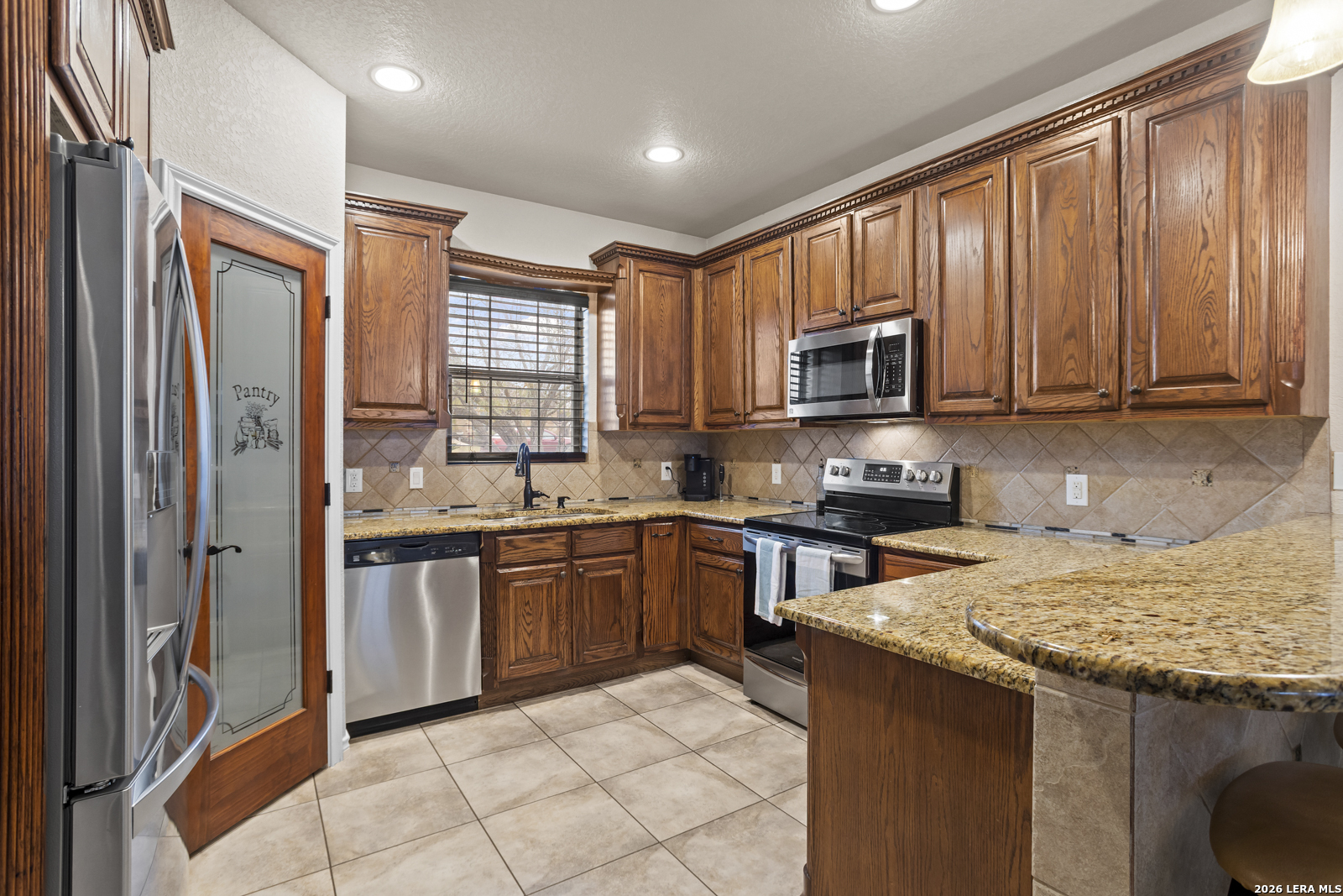 500 Wagon Train Road La Vernia, TX 78121 - Photo 12 of 44 a kitchen with stainless steel appliances granite countertop a stove top oven a sink dishwasher a refrigerator and a microwave oven