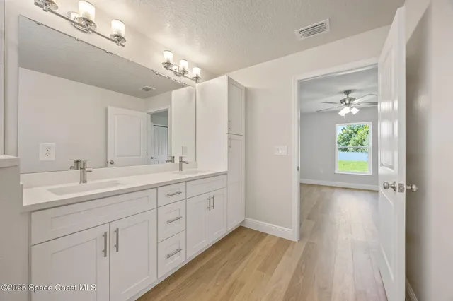 a view of an empty room and chandelier fan