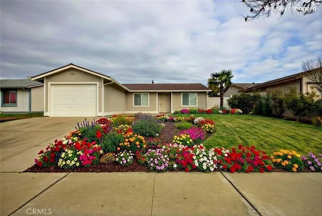 a front view of house and yard with beautiful flowers