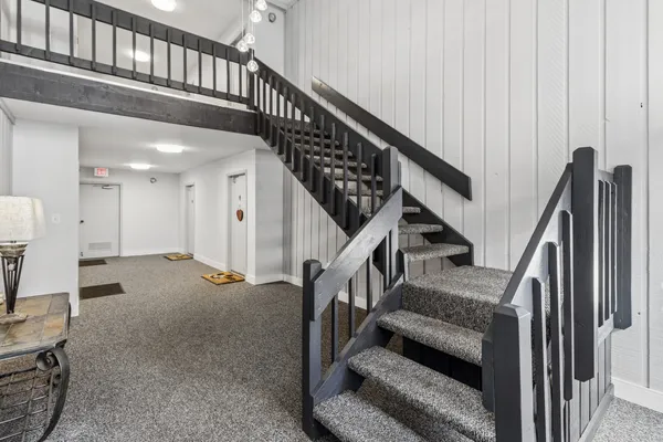 a view of staircase with lots of frames on wall and a chandelier