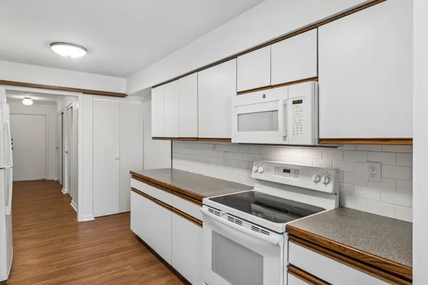 a kitchen with granite countertop white cabinets and white appliances