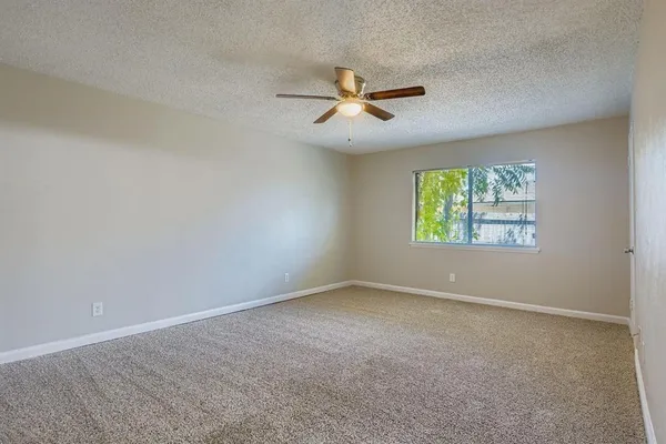 an empty room with a window and a fan