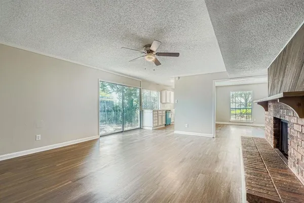 an empty room with wooden floor a chandelier fan and windows