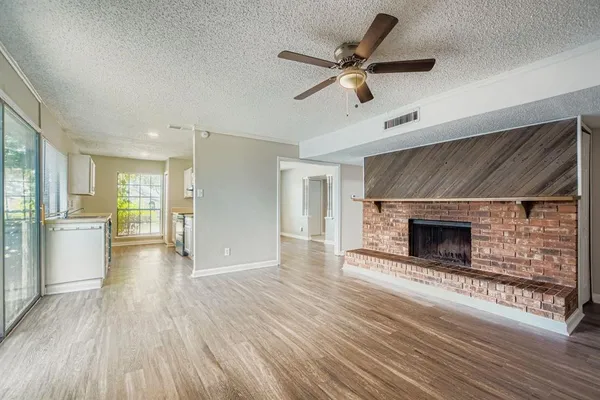 a view of a livingroom with a fireplace a ceiling fan and windows