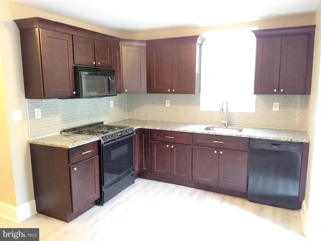 a kitchen with stainless steel appliances granite countertop wooden cabinets a stove top oven a sink and dishwasher