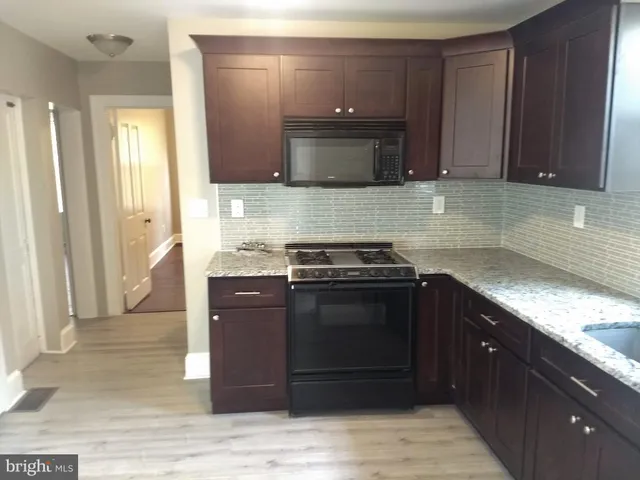 a kitchen with stainless steel appliances granite countertop wooden cabinets and a stove top oven