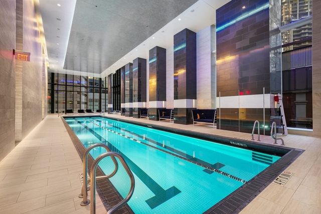a view of swimming pool with chairs in front of building