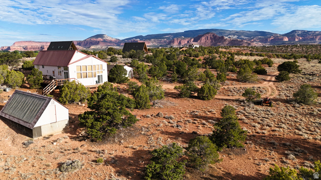 358 South Sky Drive Torrey, UT 84775 - Photo 75 of 82 Sprawling desert property featuring a white residence with a red metal roof, a secondary A-frame structure, and a detached greenhouse with a sloped roof