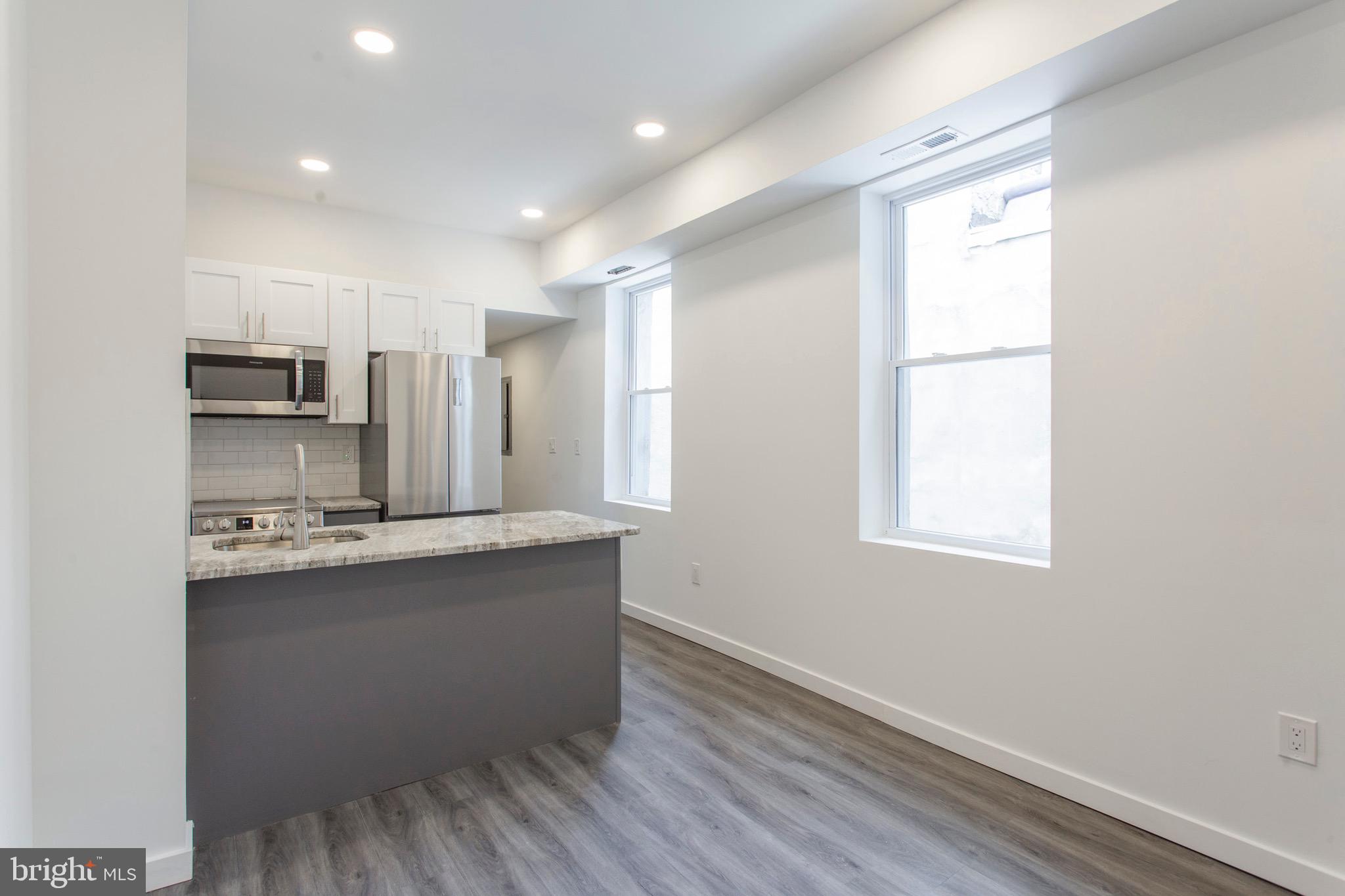 2131 North 8th Street, Unit 2 Philadelphia, PA 19122 - Photo 3 of 19 a kitchen with kitchen island a sink appliances and cabinets