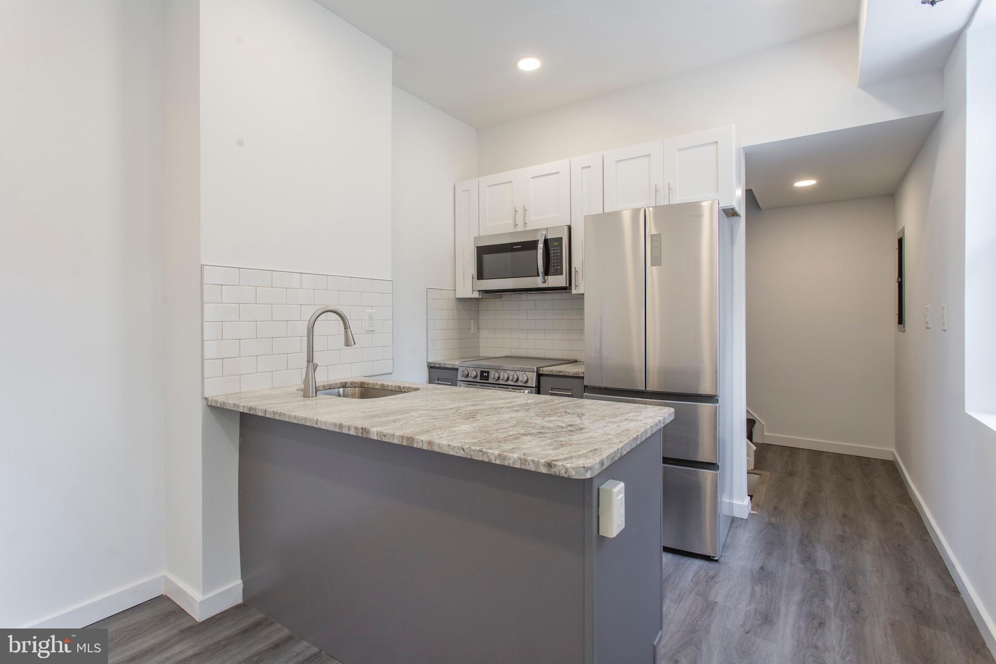 2131 North 8th Street, Unit 2 Philadelphia, PA 19122 - Photo 4 of 19 a kitchen with stainless steel appliances granite countertop a sink refrigerator and microwave