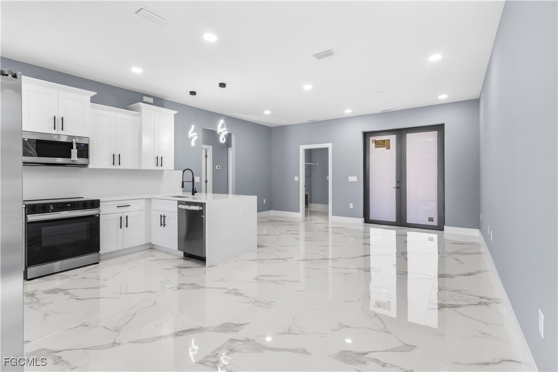 714 Hamilton Avenue Lehigh Acres, FL 33972 - Photo 17 of 30 a kitchen with stainless steel appliances a stove a sink a microwave a refrigerator and cabinets
