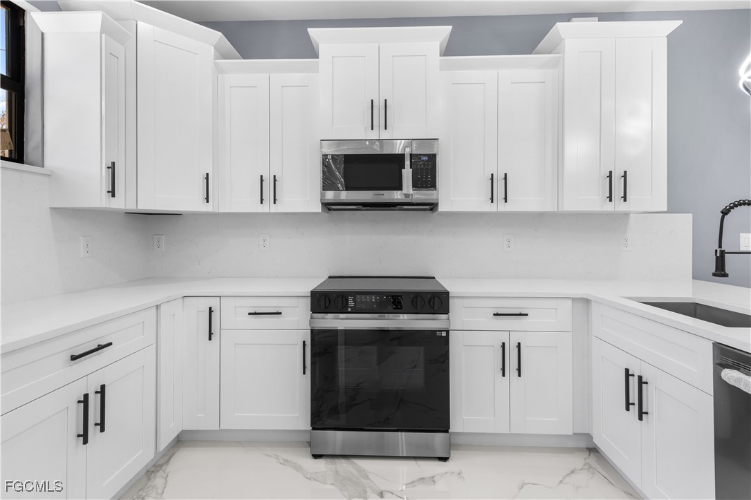 714 Hamilton Avenue Lehigh Acres, FL 33972 - Photo 19 of 30 a kitchen with white cabinets and stainless steel appliances