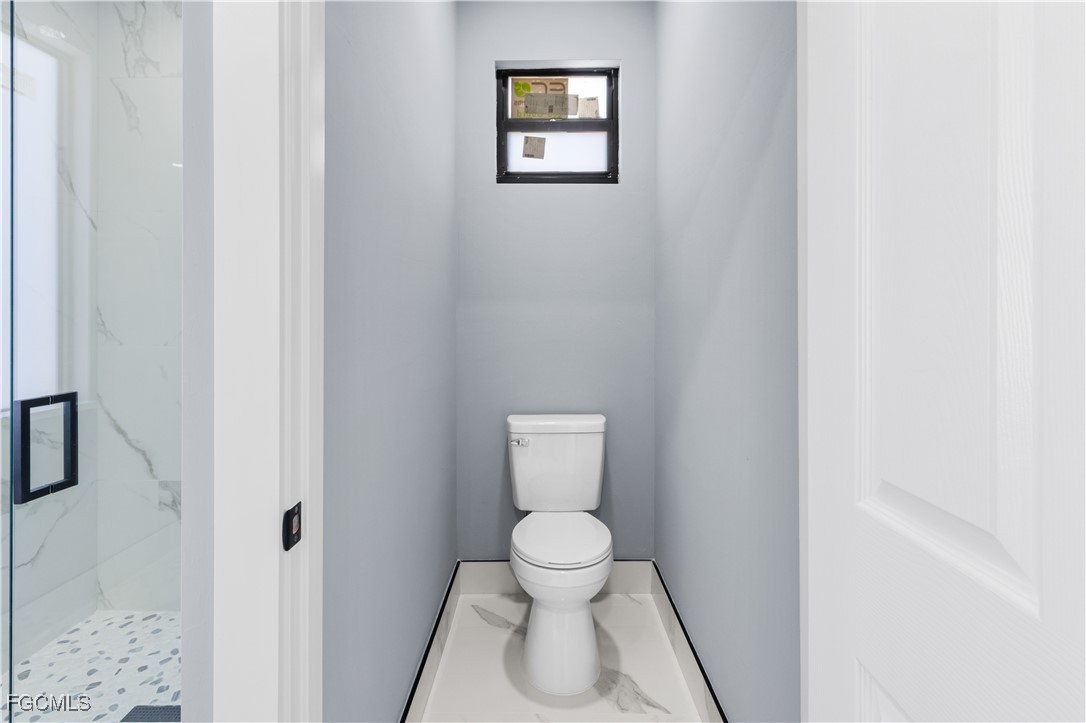 714 Hamilton Avenue Lehigh Acres, FL 33972 - Photo 26 of 30 a bathroom with a toilet and a painting on the wall