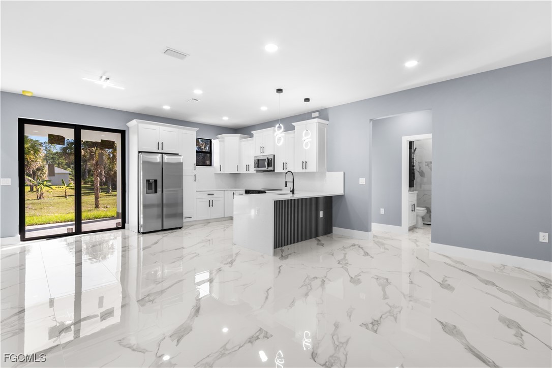 714 Hamilton Avenue Lehigh Acres, FL 33972 - Photo 5 of 30 a large kitchen with stainless steel appliances kitchen island granite countertop a refrigerator and cabinets