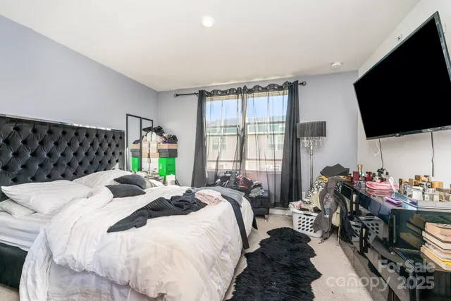 a bedroom with bed a flat tv screen and a large window with the garden view