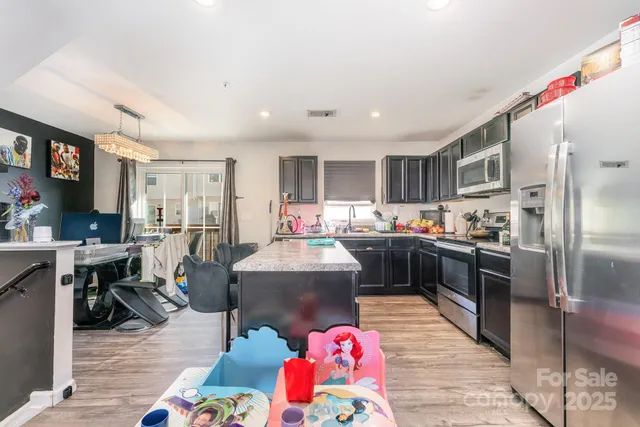 a kitchen with kitchen island stainless steel appliances a stove refrigerator sink dining table and chairs