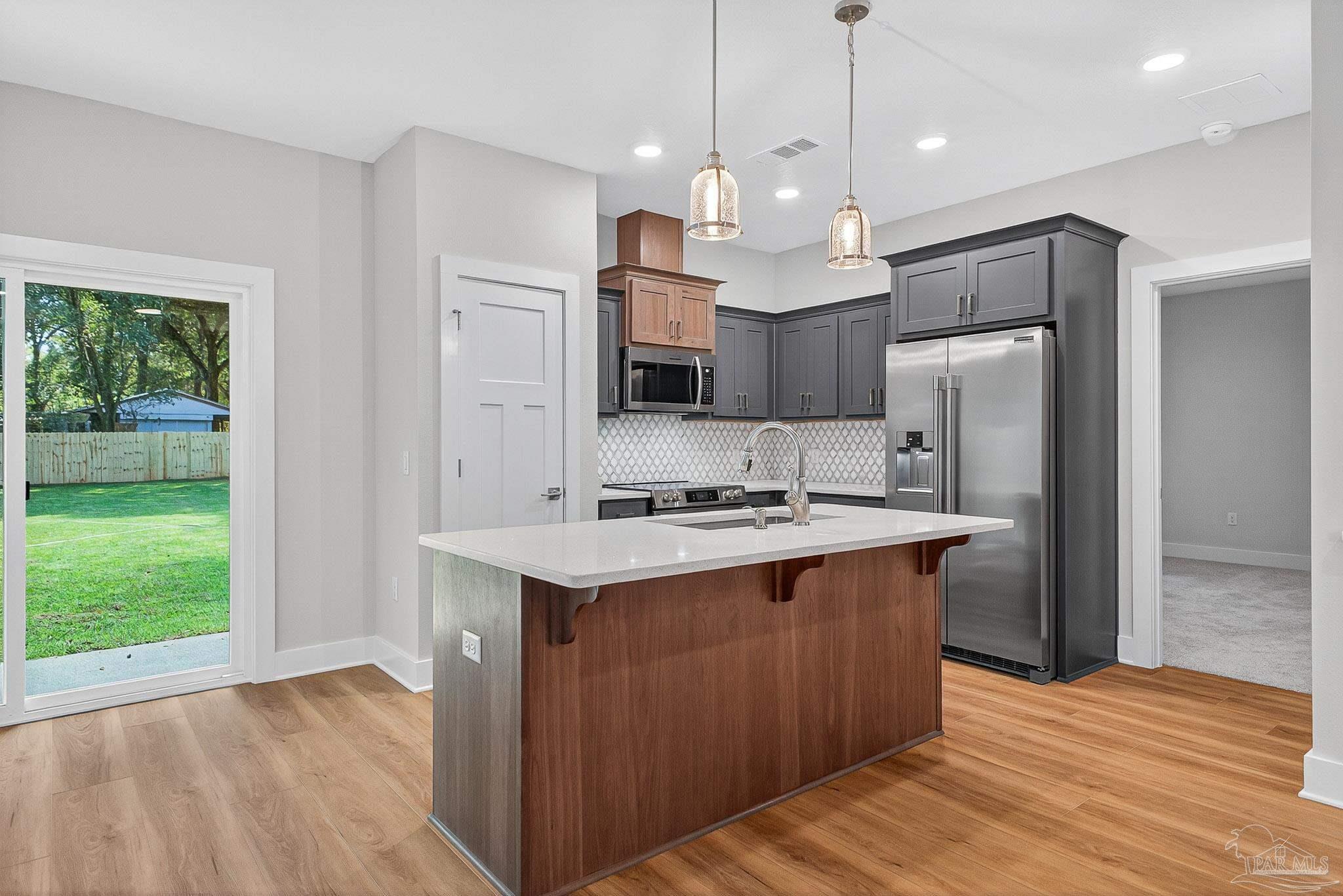6115 Carroll Road Milton, FL 32583 - Photo 17 of 57 a kitchen with kitchen island a sink stainless steel appliances and wooden floor