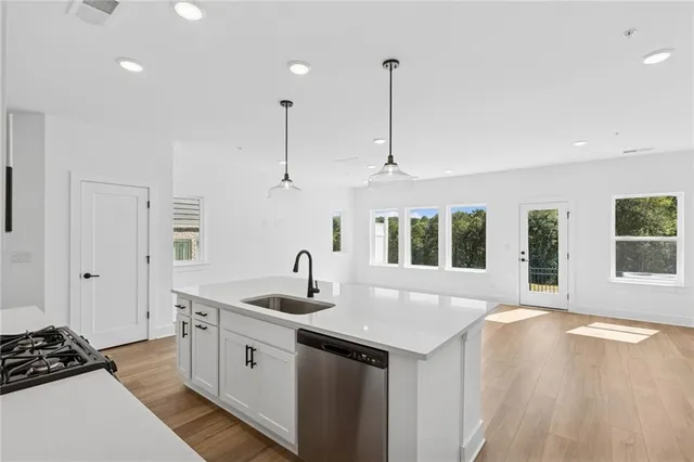 a kitchen with stainless steel appliances a sink a stove a refrigerator cabinets and wooden floor