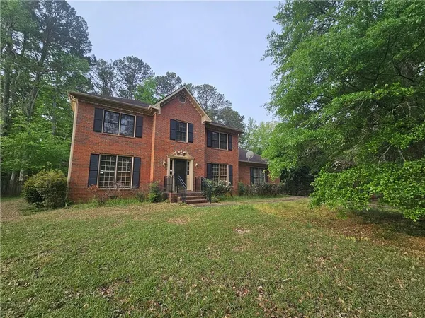 a view of a yard in front of a brick house with large windows
