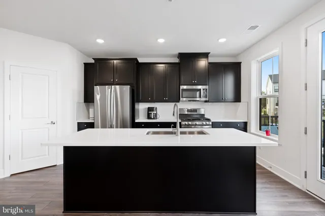 a kitchen with kitchen island stainless steel appliances a sink and refrigerator