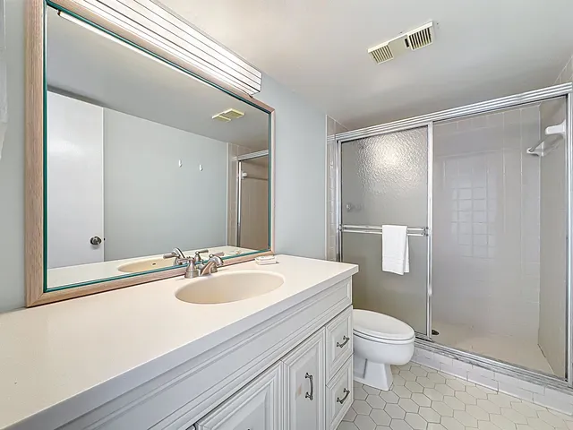 a bathroom with a sink a toilet a mirror and shower