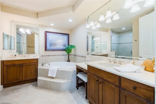 a bathroom with a sink vanity granite tub and a mirror