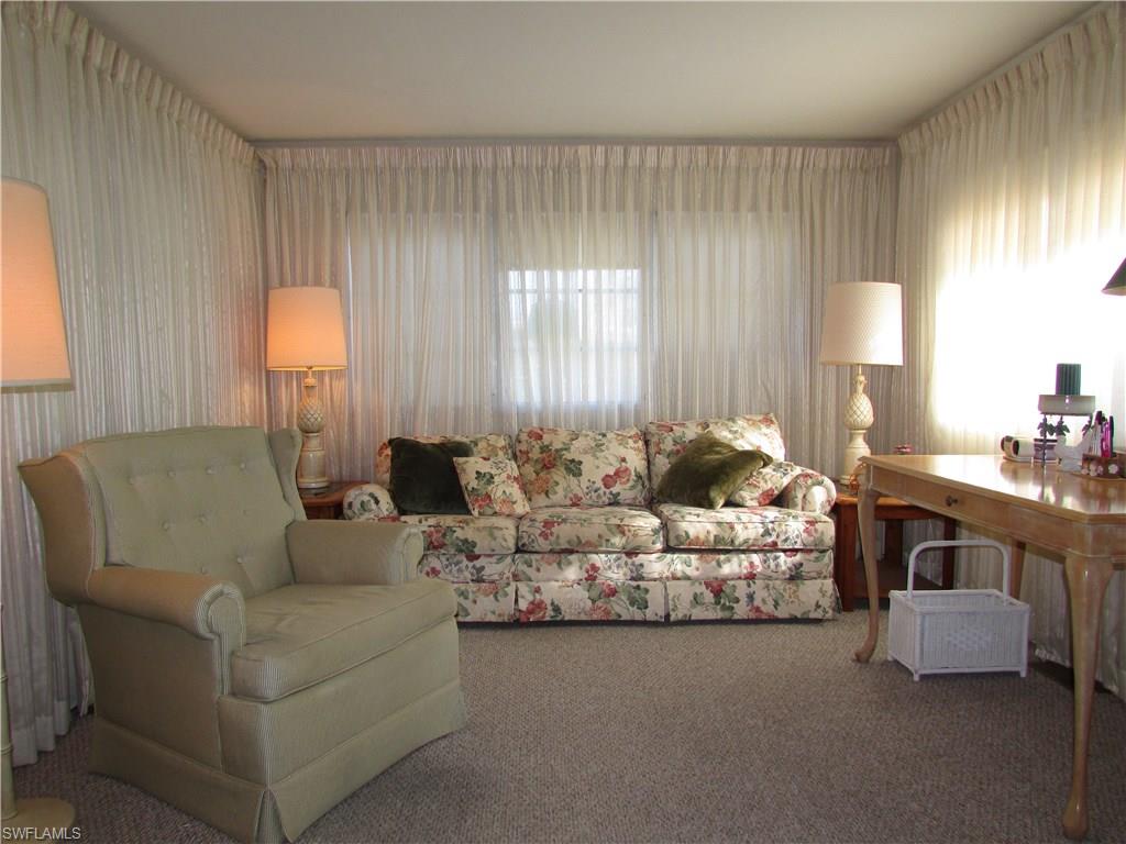 113 Enchanting Boulevard, Unit E113 Naples, FL 34112 - Photo 2 of 11 a living room with furniture and large windows