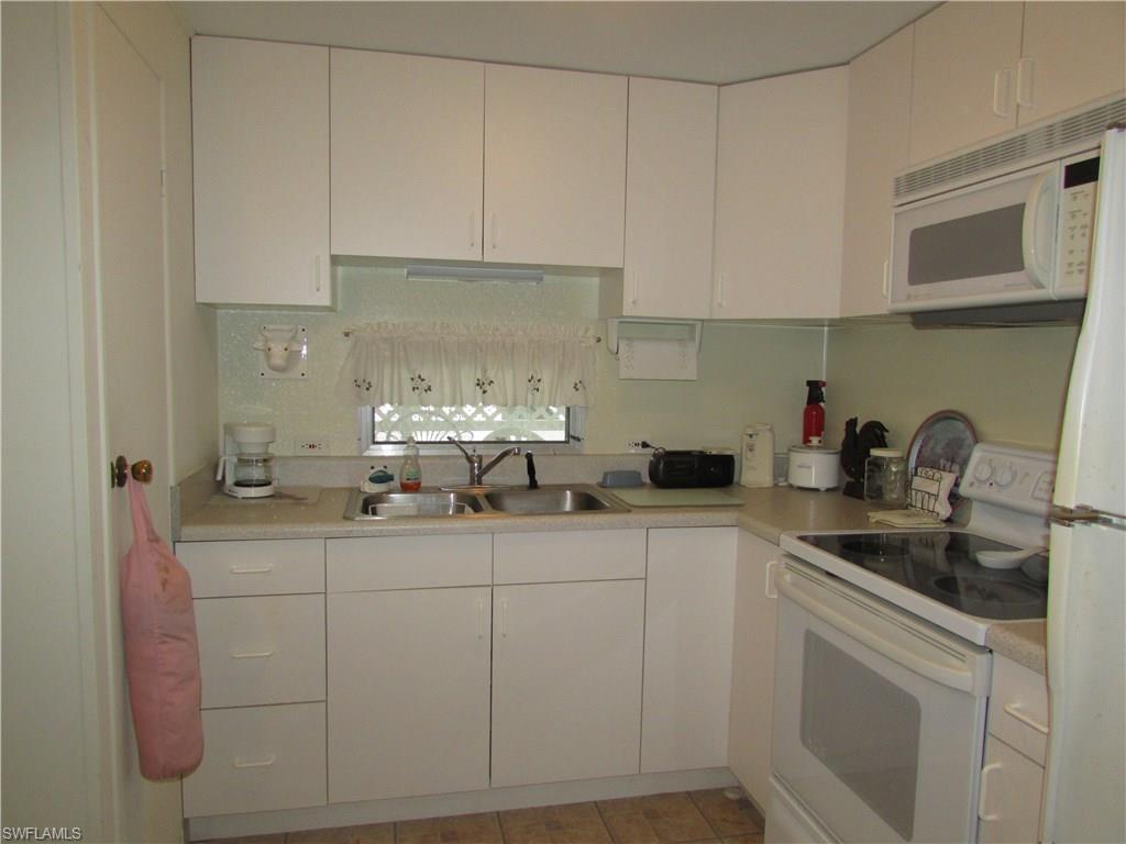 113 Enchanting Boulevard, Unit E113 Naples, FL 34112 - Photo 3 of 11 a kitchen with stainless steel appliances granite countertop white cabinets sink and dishwasher
