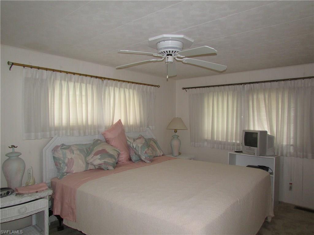 113 Enchanting Boulevard, Unit E113 Naples, FL 34112 - Photo 5 of 11 a bedroom with a large bed and a chandelier